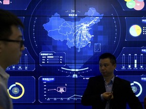 In this April 26, 2018, photo, visitors stand in front of an electronic data display showing a map of China at the Global Mobile Internet conference in Beijing. A California-based security-research firm said Wednesday, July 11, 2018, that it found evidence that an elite Chinese government-linked hacking team has penetrated computer systems belonging to Cambodia's election commission, opposition leaders and media in the months leading up to Cambodia's July 29 election.