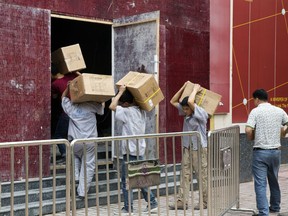 Workers carry boxes of LED lights into a renovation site in Beijing, China, Tuesday, July 3, 2018. Barring a last-minute breakthrough, the Trump administration on Friday will start imposing tariffs on $34 billion in Chinese imports. And China will promptly strike back with tariffs on an equal amount of U.S. exports.