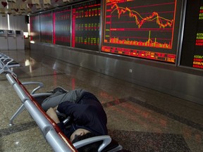 An investor rests near a stock market ticker at a brokerage in Beijing, China, Wednesday, July 25, 2018. Asian stock markets were mostly higher Wednesday after Wall Street gained on strong corporate earnings.