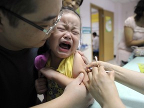 FILE - In this Sept. 11, 2010 file photo, a child cries while receiving a shot of measles vaccine at a health station in Hefei in central China's Anhui province. China's No. 2 leader has ordered an investigation of its vaccine industry after violations by a rabies vaccine producer prompted a public outcry following scandals over shoddy drugs and food. (Chinatopix via AP)