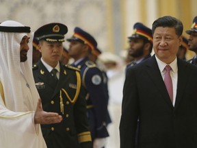 Sheikh Mohamed bin Zayed Al Nahyan, Crown Prince of Abu Dhabi, left,  gestures to Chinese President Xi Jinping, right, with Deputy Supreme Commander of the UAE Armed Forces, second left after reviewing the Guard of Honour, at the Presidential Palace in Abu Dhabi, United Arab Emirates, Friday, July 20, 2018.