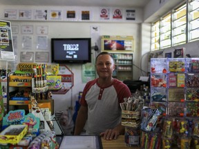 In this July 24, 2018 photo, Sergio Vega, owner of the Olympia corner store poses for a photo at his business in Adjuntas, Puerto Rico. Vega's shop is power by a solar energy system provided by the nonprofit environmental group Casa Pueblo.