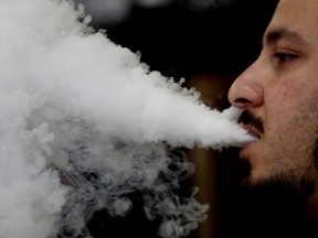 A man breathes vape from an e-cigarette.