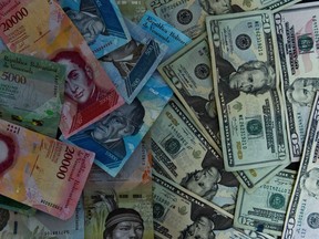 View of Venezuelan bolivar banknotes and US dollar bills in Caracas on August 2, 2018. Venezuela's government on Thursday loosened the tight currency controls it first put in place 15 years ago, with the pro-government Constituent Assembly announcing the passage of a decree authorizing money exchange operations.