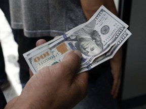 A Turkish waits to change his US dollars with Turkish liras inside a currency exchange shop in Ankara, Turkey, Friday, Aug. 10, 2018. A financial shockwave ripped through Turkey on Friday as its currency nosedived on concerns about its economic policies and a dispute with the U.S., which President Donald Trump stoked further with a promise to double tariffs on the NATO ally.