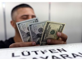 An official checks US dollar banknotes before changing them for Turkish lira currency inside a currency exchange office in Ankara, Turkey, Friday, Aug. 17, 2018. Turkey and the United States exchanged new threats of sanctions Friday, keeping alive a diplomatic and financial crisis.