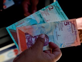 A man shows new five Bolivar-notes in Caracas on August 20, 2018.  Caracas is issuing new banknotes after lopping five zeroes off the crippled bolivar, casting a pall of uncertainty over businesses and consumers across the country.