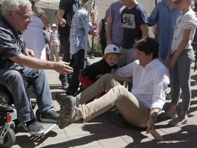 Duncan Mayor Phil Kent reaches out to grab Prime Minister Justin Trudeau's hand after his slips while trying to stand up after talking to Kent at the Duncan Farmers Market in Duncan, B.C., on Saturday, August 4, 2018.