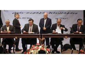 FILE - In this July 3, 2017 file photo, Chairman and CEO of France's Total SA Patrick Pouyanne, seated second left, managing director of Iran's Petropars Hamid Akbari, left, CEO of National Iranian Oil Company Ali Kardor, second right, and President of China's CNPC International Lv Gongxun sing the documents of a contract to develop an Iranian gas field, as Iranian Oil Minister Bijan Zanganeh, standing at center, and Chinese ambassador to Tehran Pang Sen look on, in Tehran, Iran. Iran's oil minister said Monday, Aug. 20, 2018, that France's oil giant Total SA has pulled out of Iran after cancelling its $5 billion, 20-year agreement to develop the country's massive South Pars offshore natural gas field over renewed U.S. sanctions.