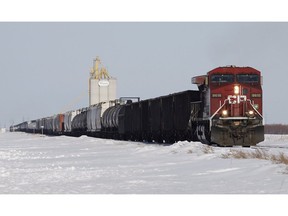 Grain and oil rail cars pass by a grain elevator in Rosser, Man., just outside Winnipeg, March 24, 2014.