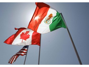 In this April 21, 2008 file photo, national flags of the United States, Canada, and Mexico fly in the breeze in New Orleans. The hurry-up-and-wait uncertainty surrounding Canada's return to the NAFTA talks is entering a new week as Ottawa's partners in the trilateral deal push forward with their one-on-one negotiations.