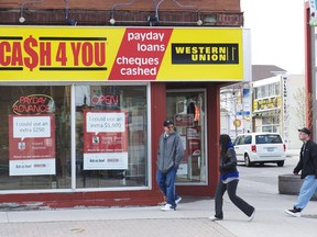 People walk pass a pay day loan store in Oshawa, Ont., on May 13, 2017.