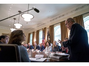 White House chief economic adviser Larry Kudlow, right, accompanied by Secretary of Veterans Affairs Robert Wilkie, left, and CIA Director Gina Haspel, second from left, gives a report on the economy during a cabinet meeting with President Donald Trump, background at left, in the Cabinet Room of the White House, Thursday, Aug. 16, 2018, in Washington.