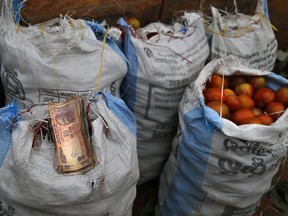 FILE - In this Dec. 30, 2016 file photo, smaller denomination currency notes are placed on a sack of tomatoes, put up for sale at a wholesale vegetable market in Bangalore, India. The Indian rupee has fallen to an all-time low against the U.S. dollar amid worries over Turkey's growing financial crisis. Indian Economic Affairs Secretary Subhash Chander Garg told reporters that there was "nothing at this stage to worry" about after the rupee reached 70.1 to the dollar earlier Tuesday, Aug. 14, 2018.