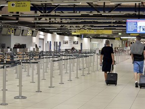 Passenger walk through the empty departure hall of the Schoenefeld airport near Berlin Friday, Aug. 10, 2018 when several flights of Irish Ryanair airline had been cancelled due to a strike of pilots.