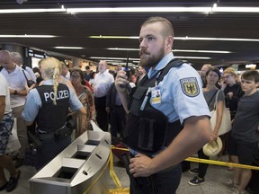 Police and passenger wait in hall of terminal 1 of the Frankfurt, Germany, Airport, Tuesday, Aug. 7, 2018 after parts of a terminal were evaucated over concerns that at least one person may have entered the facility's security area unchecked.