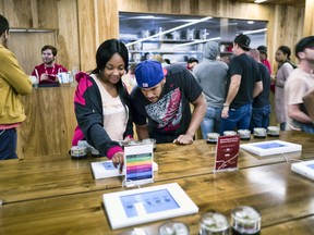 File - In this May 19, 2018 file photo tourists Randy Wilkie and Keya Cole from Buffalo, New York, check out the offerings of cannabis at one of the MedMen cannabis dispensaries in Los Angeles, prior to boarding the Green Line Trips bus tour. When it comes to the taxman, California's legal pot market is getting a sluggish start. Marijuana cultivation and excise tax collections hit $48 million between April and June, state officials announced Wednesday, Aug. 15, 2018, a jump from the prior three months but well below the windfall envisioned by the state.