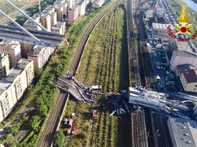 In this photo released by the Italian firefighters, rescue teams work among the rubble of the collapsed Morando highway bridge in Genoa, northern Italy, Tuesday, Aug. 14, 2018. A bridge on a main highway linking Italy with France collapsed in the Italian port city of Genoa during a sudden, violent storm, sending vehicles plunging 90 meters (nearly 300 feet) into a heap of rubble below. (Vigili Del Fuoco via AP)