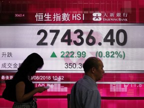 People walk past an electronic board showing Hong Kong share index outside a local bank in Hong Kong, Monday, Aug. 20, 2018. Asian stocks are mostly higher Monday as investors welcomed signs of progress in resolving the trade dispute between the U.S. and China.