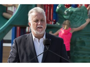 Primary school students play behind Quebec Liberal Leader Philippe Couillard as he speaks at a news conference to announce his education program for youth and families, in St-Felicien, Que., Monday, August 27, 2018.