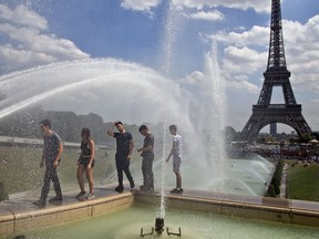 People cool off as they walk along the fountain of Warsaw near Eiffel Tower in Paris, France, Wednesday, Aug, 1, 2018. Temperatures in Paris are forecast to reach 3O degrees C (86 F) on Wednesday.
