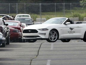 A 2019 GT Mustang, the 10 millionth Mustang built by Ford drives by a group of previous model Mustangs on a parking lot at the Flat Rock Assembly plant, Wednesday, Aug. 8, 2018 in Flat Rock, Mich.