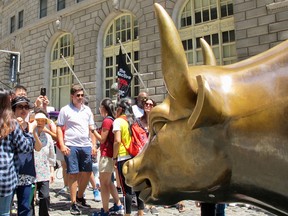 Tourists visit the Charging Bull near Wall Street in New York City.