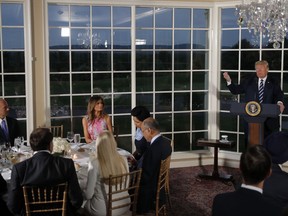 President Donald Trump speaks as he meets with business leaders, Tuesday, Aug. 7, 2018, at Trump National Golf Club in Bedminster, N.J. First lady Melania Trump, sitting at the table, listens.