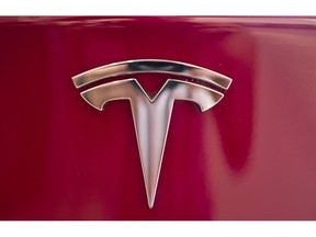 FILE- In this Aug. 8, 2018, file photo a Tesla emblem is seen on the back end of a Model S in the Tesla showroom in Santa Monica, Calif.    Tesla Inc. will remain on the public stock exchanges after CEO Elon Musk said Friday, Aug. 24, 2018 that investors have convinced him the company shouldn't go private. The eccentric and sometimes erratic CEO wrote in a late-night statement that he made the decision based on feedback from shareholders, including institutional investors, who said they have internal rules limiting how much they can sink into a private company.