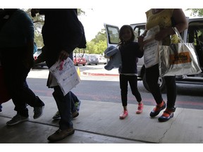 FILE - In this Monday, July 23, 2018 file photo, immigrants seeking asylum, some wearing ankle monitors, arrive at a Catholic Charities facility not long after they were reunited in San Antonio. Federal authorities' shift away from separating immigrant families caught in the U.S. illegally now means that many parents and children are quickly released, only to be fitted with electronic monitoring devices _ a practice which both the government and advocacy groups oppose for different reasons.