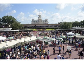 FILE - In this June 15, 2016, file photo, guests appear at the entrance to Disney's Magic Kingdom theme park in Lake Buena Vista, Fla. Disney is offering to pay full tuition for hourly workers who want to earn a college degree, finish a high school diploma or learn a new skill. The company said Wednesday, Aug. 22, 2018, that starting in the fall it will pay upfront tuition to workers who want to take online classes.