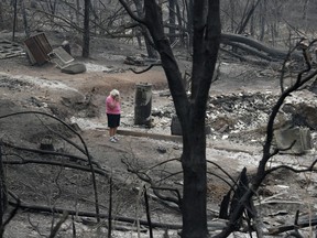 FILE- In this Aug. 9, 2018, file photo Loretta Root wipes her eyes while visiting the remains of her home in the Keswick area burned in a wildfire in Redding, Calif. "It's hard to see this," Root says of her family home. Several of Root's family members living nearby also lost their homes to the fire. Last year's wildfires in California caused roughly $12 billion in insurance claims, the most expensive year on record. But officials and experts warn that the state could be facing its toughest wildfire season yet.