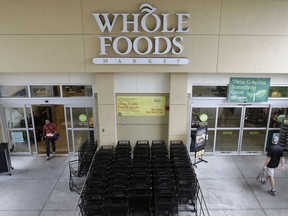 FILE- In this Aug. 28, 2017, file photo, customers shop at a Whole Foods Market in Tampa, Fla. Amazon, known for bringing items to shoppers' homes, is adding a curbside pickup option at Whole Foods for Prime members. The Whole Foods move announced Wednesday, Aug. 8, 2018, is the latest by Seattle-based Amazon.com Inc. since it took control of the grocery chain a year ago.
