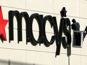 FILE- In this Feb. 12, 2018, file photo the sign on a Macy's store in Homestead, Pa., is worked on. Macy's Inc. reports earnings Wednesday, Aug. 15.