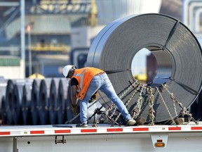 In this July 25, 2018, photo a truck driver chains down a roll of steel to his flatbed at the NUCOR Steel Gallatin plant in Ghent, Ky. The rolls, weighing as much as 20 tons, are transported one at a time. On Wednesday, Aug. 15, the Federal Reserve reports on U.S. industrial production for July.