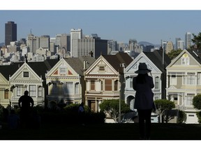 FILE- In this April 15, 2016, file photo a woman looks toward the "Painted Ladies," a row of historical Victorian homes, with the San Francisco skyline at rear at Alamo Square Park in San Francisco. The Trump administration announced new rules Thursday, Aug. 23, 2018, aimed at preventing residents in high-tax states from avoiding a new cap on widely popular state and local tax deductions.