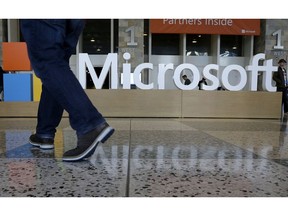 FILE - In this April 28, 2015, file photo, a man walks past a Microsoft sign set up for the Microsoft BUILD conference at Moscone Center in San Francisco. Microsoft says it's requiring its U.S. suppliers to offer their employees at least 12 weeks paid leave to care for a new child. The company announced the new parental leave policy Thursday, Aug. 30, 2018.