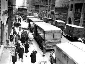 FILE - In this Nov. 29, 1943, file photo, people walk down on a street in New York's Garment District between Broadway and Eighth Avenue.  Hundreds of thousands of garment workers once toiled in the sweaty, elbow-to-elbow workshops of midtown Manhattan before the whirring of sewing machines was mostly silenced by foreign competition. But a group of New Yorkers - manufacturers, landlords, designers, politicians - want to preserve some of the bustling sewing scene by zoning the neighborhood for at least 300,000 square feet of garment workshops now serving higher-end designers. (AP Photo/File)