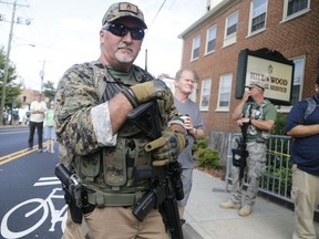 FILE - This Saturday Aug. 12, 2017 file photo, an armed militia member stands guard at a white nationalist rally in Charlottesville, Va. A social media platform can be compelled to divulge account information belonging to a woman who anonymously chatted online about plans for last summer's deadly white nationalist rally in Charlottesville, Va., a federal magistrate judge ruled Monday, Aug. 6, 2018. U.S. Magistrate Judge Joseph Spero's 28-page order says the woman's First Amendment rights to anonymous speech don't outweigh the importance of disclosing her identity to plaintiffs' attorneys suing over the rally's violence.