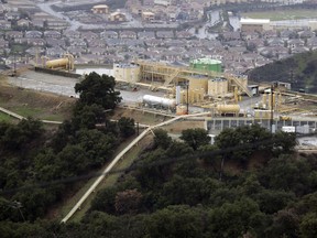 FILE - This Jan. 12, 2017 file photo shows gas gathering plant on a hilltop at the Southern California Gas Company's Aliso Canyon storage facility near the Porter Ranch neighborhood of Los Angeles. A tentative settlement has been reached in litigation stemming from a leak at a Los Angeles storage field where a massive methane release forced thousands from their homes three years ago.