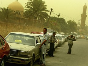 Iraqis wait in a gas line on June 30, 2008 near a gas station amid a sand storm in Baghdad, Iraq. The shortage in gas led to massive queues and a flourishing black market trade of fuel in Baghdad.