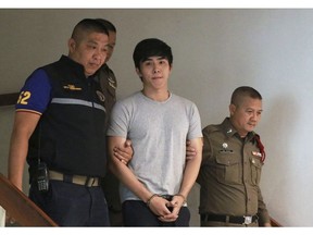 In this Aug. 10, 2018, photo, actor Jiratpisit Jaravijit, center, is escorted by Thai police officers to leave the Crimes Suppression Division in Bangkok, Thailand. Thai authorities are expected to step up their investigation of a financial scam involving the alleged theft of about $25 million worth of bitcoins from a Finnish investor who police say was bilked with promises of high returns from investments in a casino in Macau and in another cryptocurrency. The case, which surfaced with the arrest in a shopping mall parking lot of a young soap opera actor suspected of colluding with his sister and brother, has prompted Thailand's central bank to warn investors against risks of bitcoin-related scams, underscoring the challenge for regulators trying to keep up with the fast-growing cryptocurrency markets.