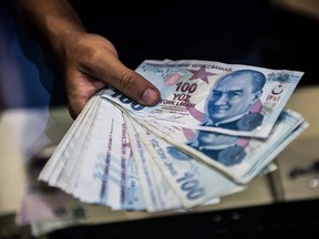 A teller holds Turkish lira banknotes at a currency exchange office in Istanbul on August 13, 2018