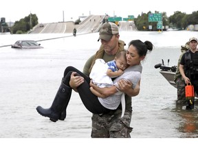 FILE - In this Aug. 27, 2017 file photo, Houston Police SWAT officer Daryl Hudeck carries Catherine Pham and her 13-month-old son Aiden, asleep in her arms, after rescuing them from their home surrounded by floodwaters from Tropical Storm Harvey in Houston, Texas. Hurricane Harvey roared onto the Texas shore nearly a year ago, but it was a slow, rainy roll that made it a monster storm. Federal statistics show some parts of the state got more than 5 feet of rain in five days. Harvey killed dozens and swamped a section of the Gulf Coast that includes Houston, the nation's fourth largest city, causing billions of dollars in damage.