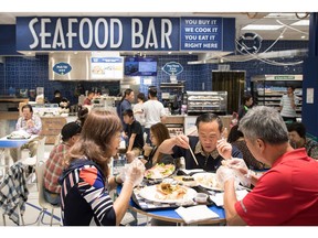 People eat at a seafood bar at T&T Supermarket's newest location, in Richmond, B.C. Grocery stores increasingly blur the line between supermarkets and restaurants with large chains adding take-out meals to their shelves, hot food counters where chefs make dishes to order and even full-service restaurants.