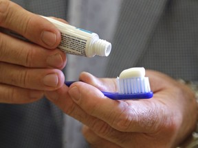 In this photo taken Friday, Aug. 3, 2018, Philippe Hujoel, a dentist and University of Washington professor, holds a toothbrush and toothpaste in an office at the school in Seattle. Dental health experts worry that more people are using toothpaste that skips the most important ingredient - the fluoride - and leaves them at a greater risk of cavities.