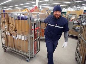 Canada Post delivery agent Wayne Chopp moves a cart full of parcels at the South West Depot in Winnipeg, Man.