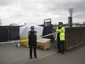 FILE - In this March 13, 2018, file photo, police officers guard a cordon around a police tent covering a supermarket car park pay machine near the spot where former Russian spy Sergei Skripal and his daughter were found critically ill following exposure to the Russian-developed nerve agent Novichok in Salisbury, England. The United States will impose sanctions on Russia for the country's use of a nerve agent in an assassination attempt on a former Russian spy and his daughter. The State Department says Aug. 8, sanctions will be imposed on Russia as the country used chemical or biological weapons in violation of international law.