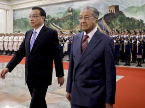 Malaysia's Prime Minister Mahathir Mohamad, right, walks with Chinese Premier Li Keqiang after reviewing an honor guard during a welcome ceremony at the Great Hall of the People in Beijing, Monday, Aug. 20, 2018.