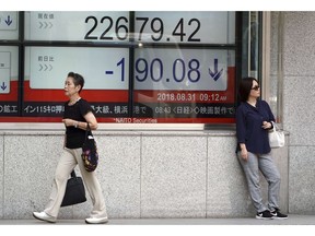 Woman walk past an electronic stock board showing Japan's Nikkei 225 index at a securities firm Friday, Aug. 31, 2018, in Tokyo. Asian shares fell Friday following a report that the Trump administration could put tariffs on $200 billion in Chinese goods as early as next week.